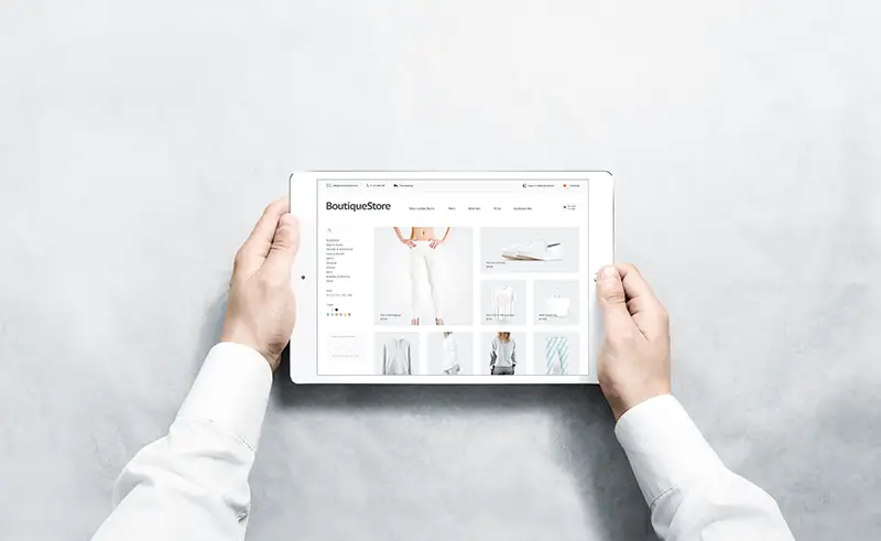 Hands holding tablet with fashion webstore mock up on screen